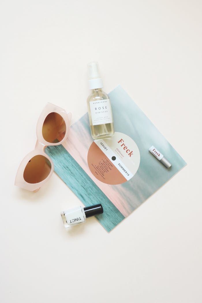 about-02 High-angle flatlay of summer essentials including sunglasses and skincare products.