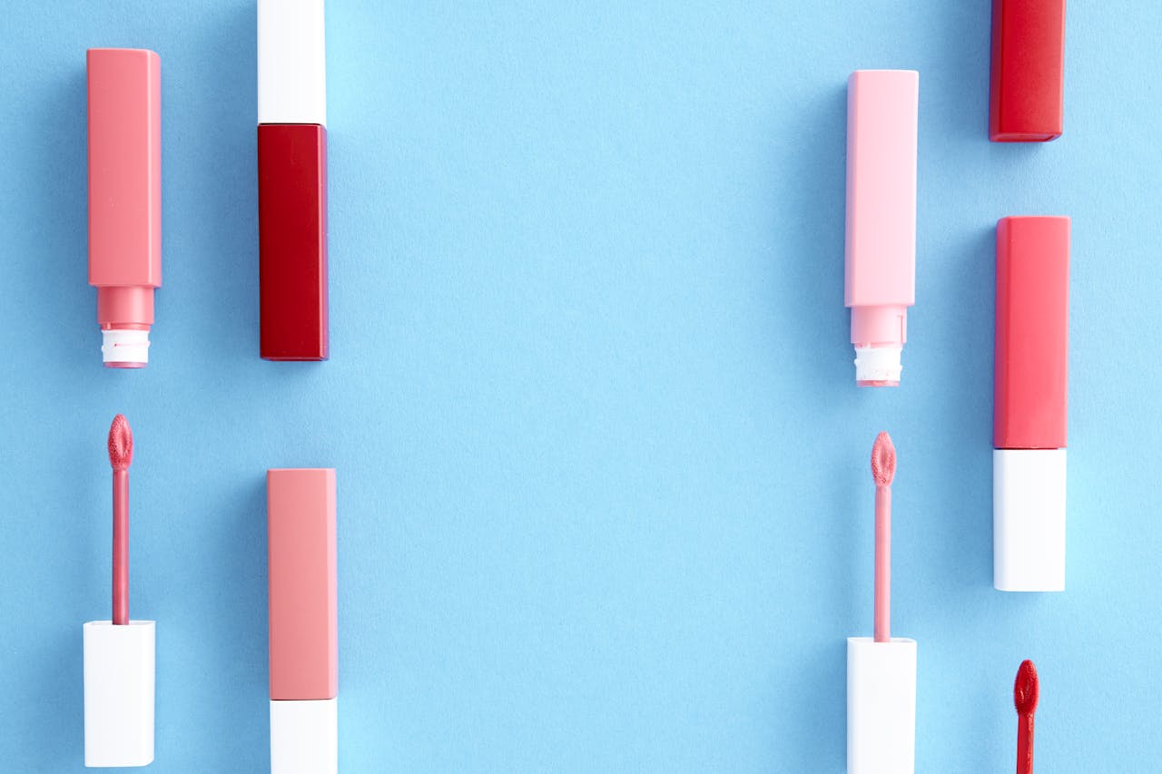 about-01 Colorful lip gloss tubes laid out on a bright blue background, showcasing modern cosmetics.